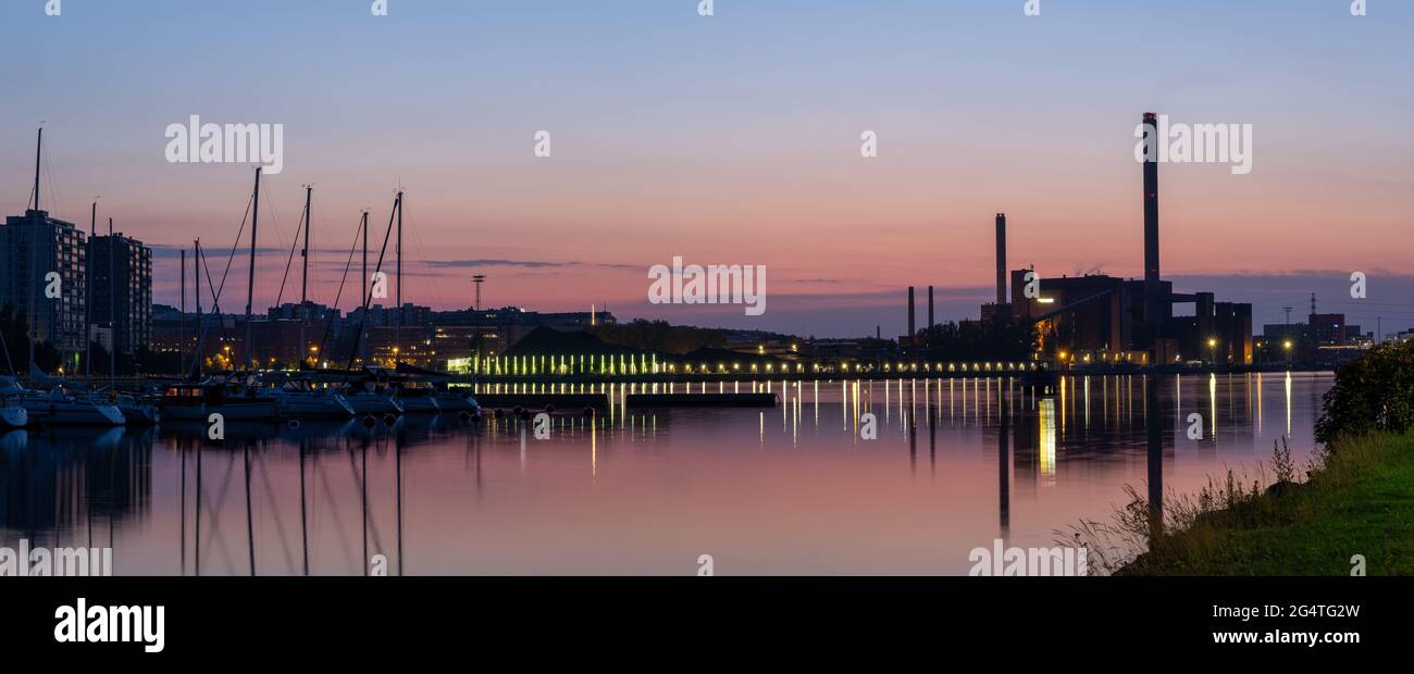 Helsinki / Finlandia - 22 GIUGNO 2021: Uno splendido skyline notturno della città contro il cielo colorato. Una vecchia centrale che getta riflessioni sull'acqua. Foto Stock