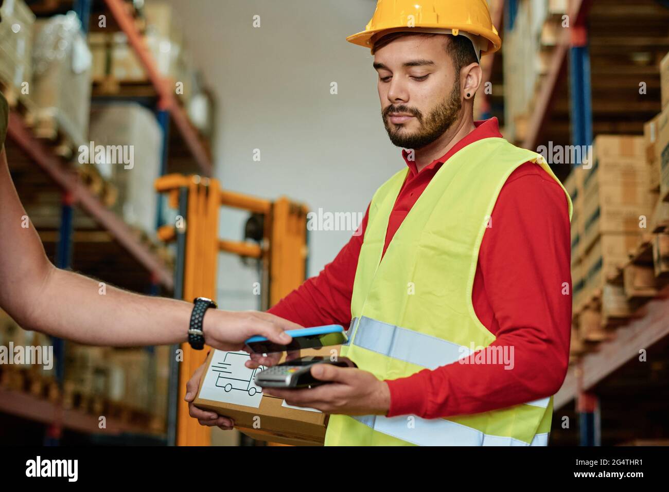 Addetto al magazzino che esegue la scansione del codice a barre sullo smartphone Foto Stock