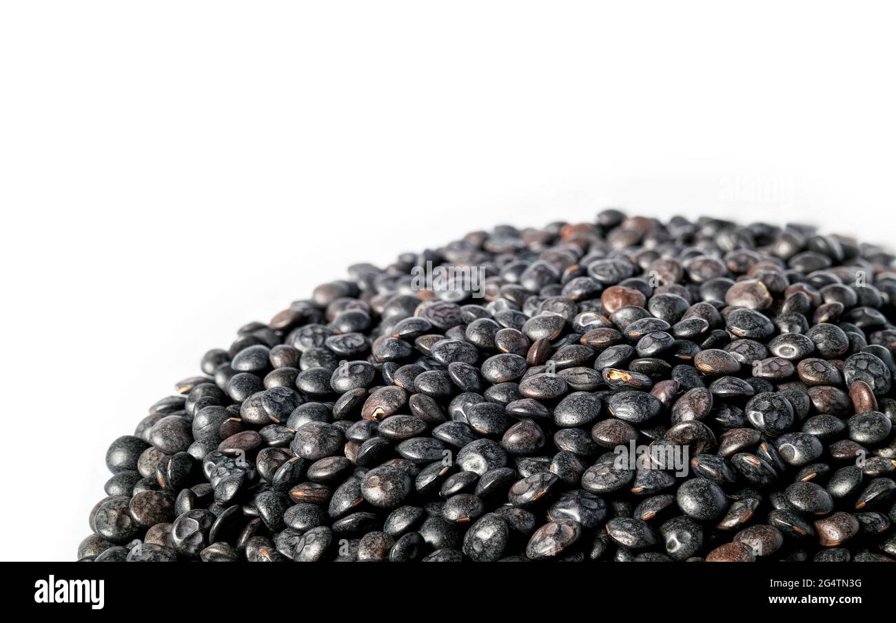 Pila di lenticchie di Beluga, primo piano. Molte piccole lenticchie nere organiche. Legume dal sapore terroso, consistenza solida e alto contenuto proteico. Utilizzato come contorno, in sou Foto Stock