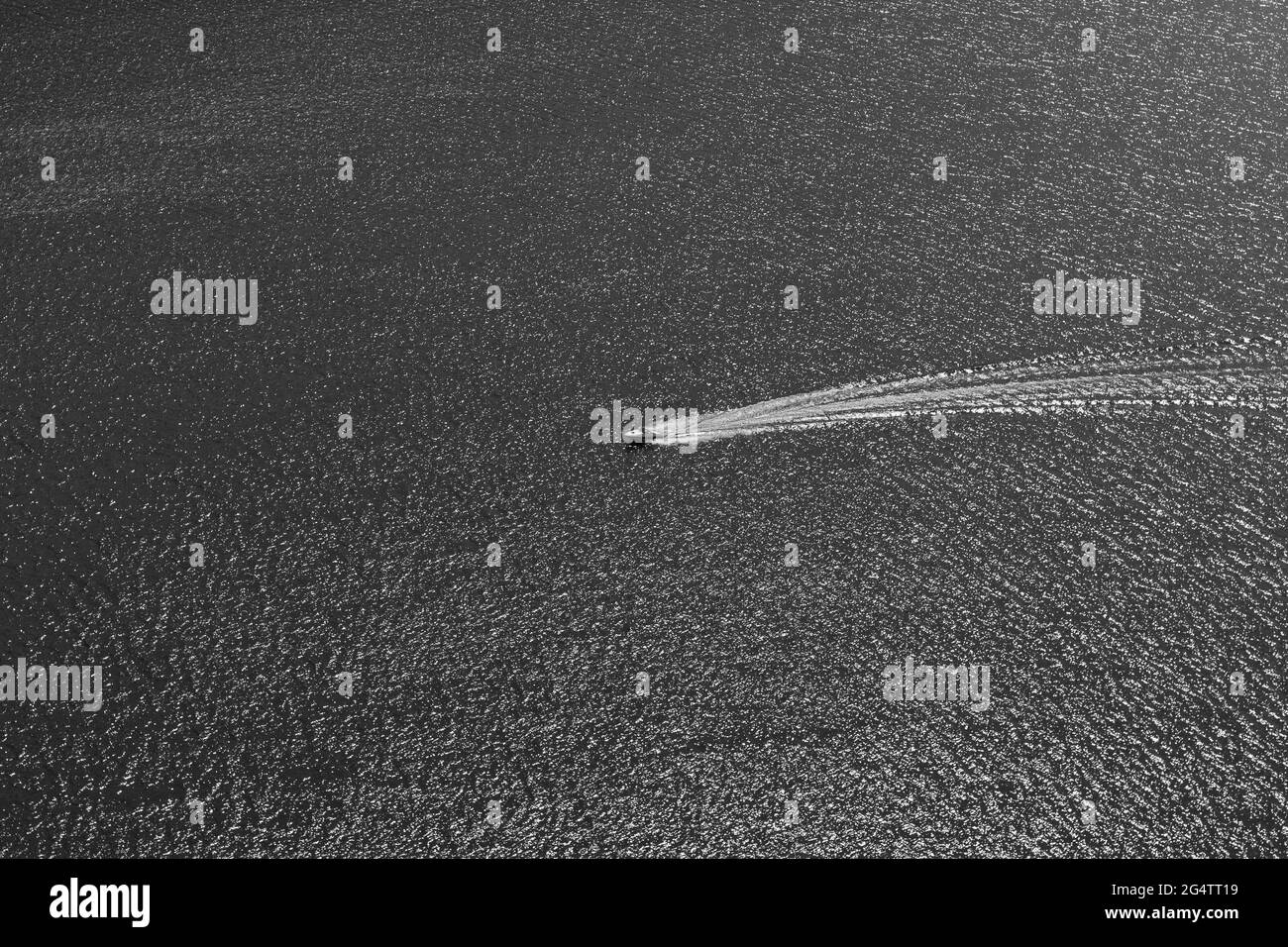 Barca sul lago navigando su acqua ondulato minimalista vista in bianco e nero. Foto Stock