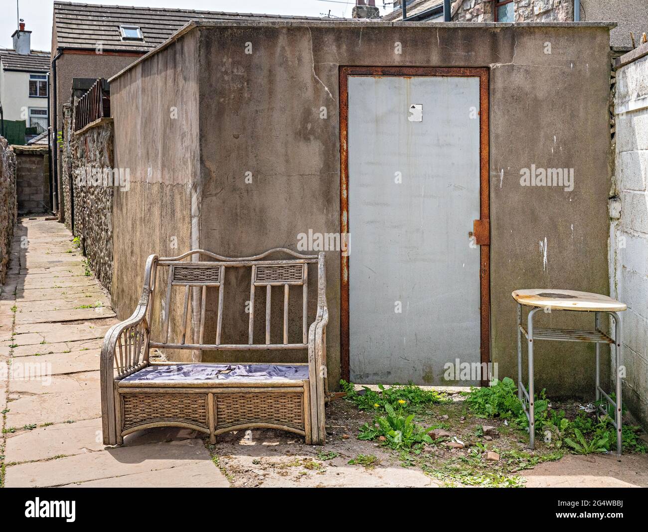 Vecchio sedile in rattan e tavolo scartati in città strada posteriore Foto Stock