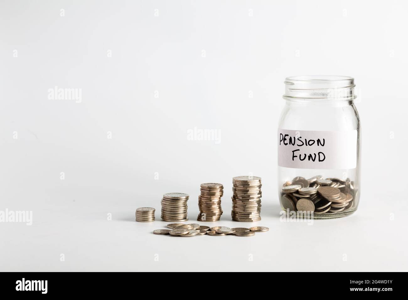 Monete accatastate accanto a un vaso vuoto con un'etichetta per il fondo pensione. Pensione, finanziaria, risparmio, economia, concetto di investimento Foto Stock