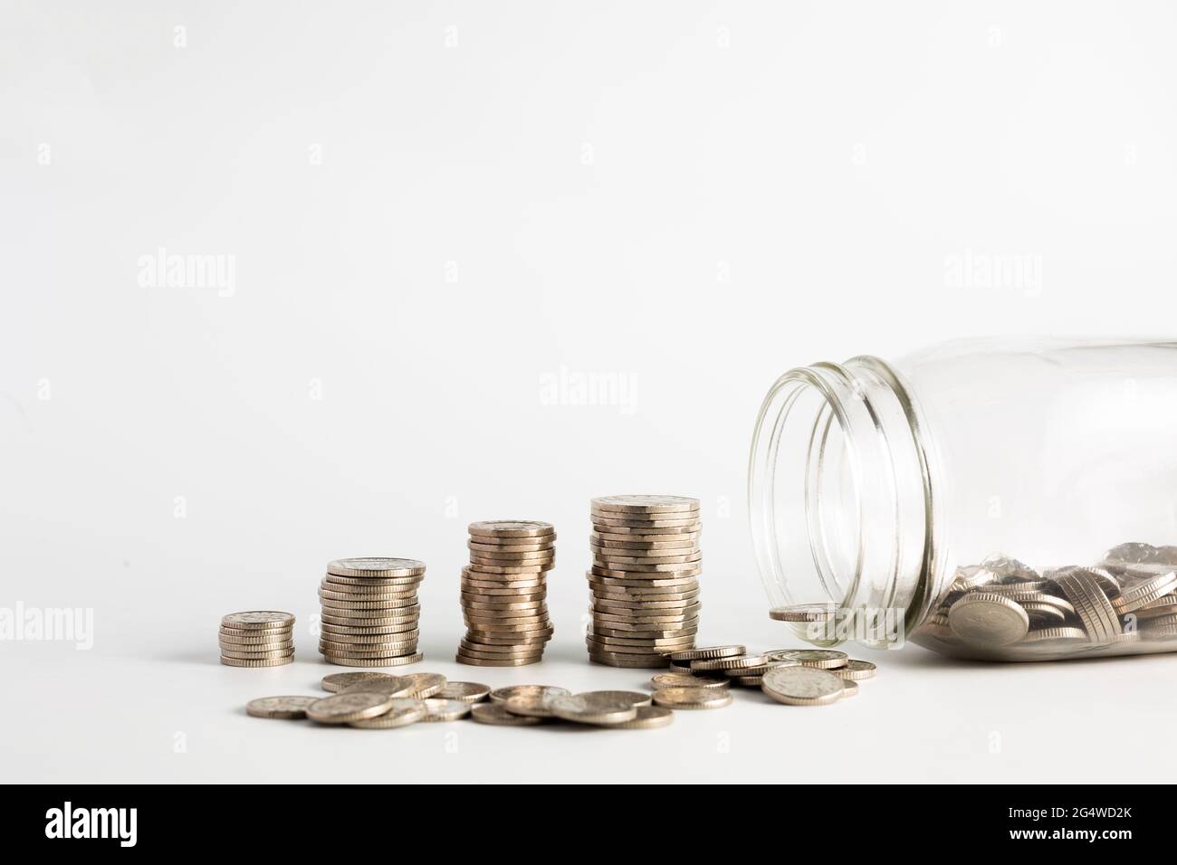 Monete accatastate vicino ad un vaso vuoto mezzo con le monete dentro e con un'etichetta su detto fondo di pensione. Pensione, finanziaria, risparmio, economia, investimenti conc Foto Stock