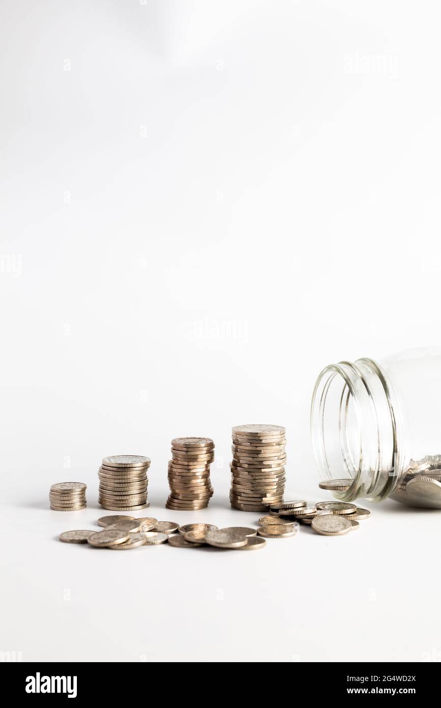 Monete accatastate accanto a un vaso vuoto con un'etichetta per il fondo pensione. Pensione, finanziaria, risparmio, economia, concetto di investimento Foto Stock