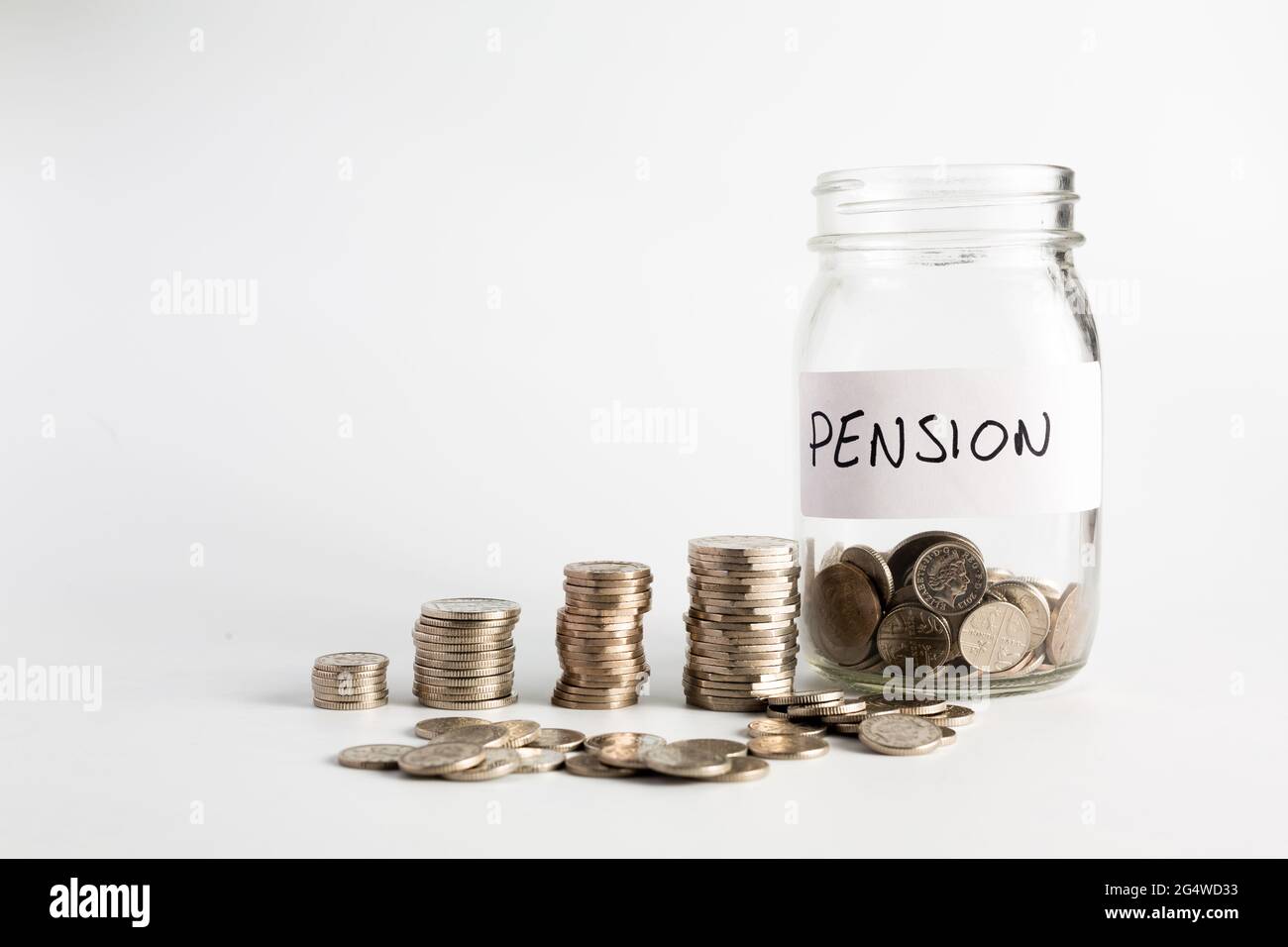 Monete accatastate accanto a un vaso vuoto con un'etichetta per il fondo pensione. Pensione, finanziaria, risparmio, economia, concetto di investimento Foto Stock