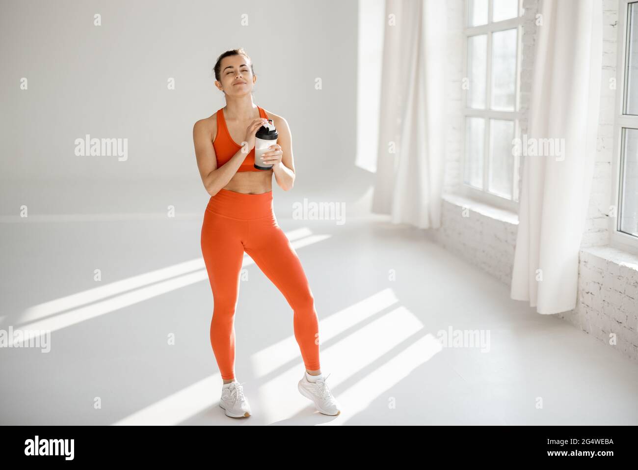 Donna sportiva con shaker proteico in palestra Foto Stock