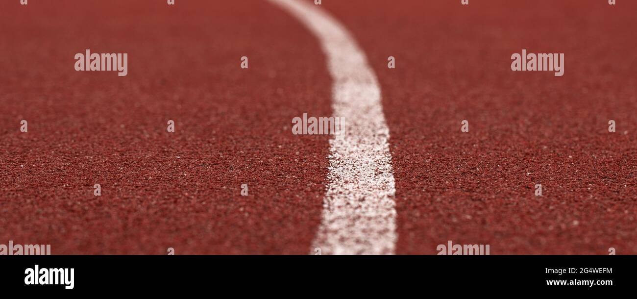 Pista da corsa rossa con texture in gomma bianca su sfondo a trama di stadio Foto Stock