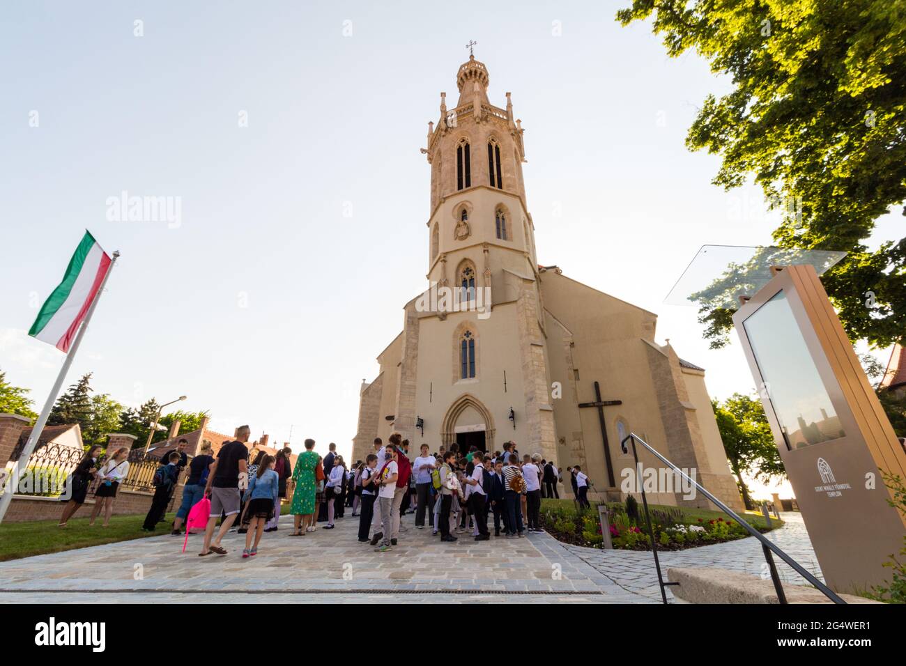 Bambini e genitori si riuniscono di fronte a Szent Mihaly-templom (chiesa di San Michele) per il servizio di fine anno scolastico, Sopron, Ungheria Foto Stock