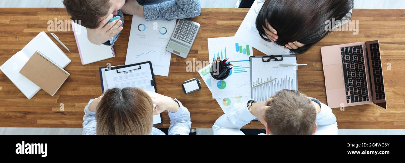 Gruppo di persone che siedono a tavola e tengono la testa vista dall'alto Foto Stock