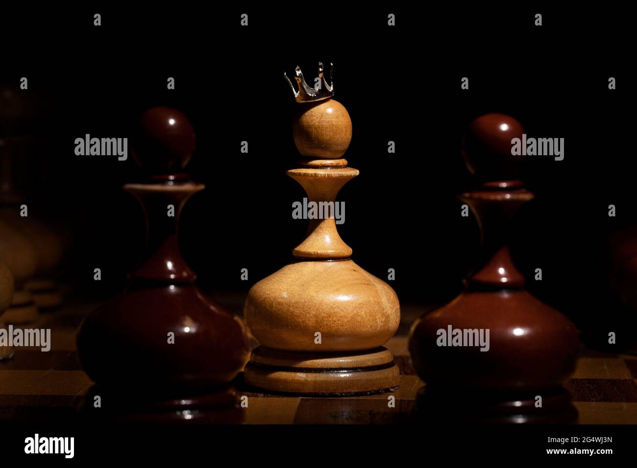 pawn con una corona su sfondo scuro. scacchi vecchi. concetto di business Foto Stock