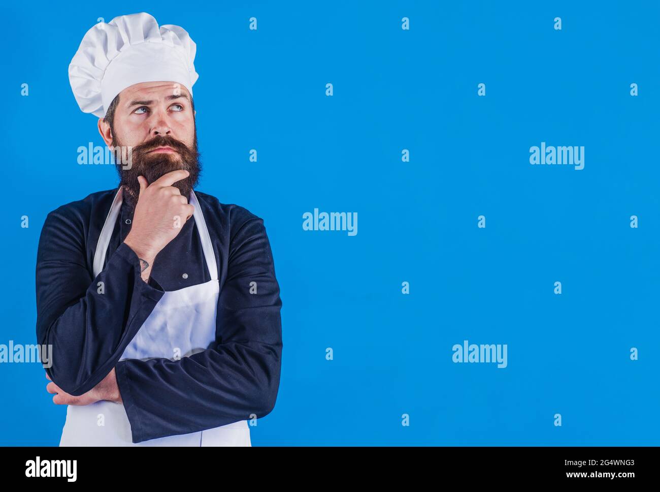 Cuoco serio bearded in uniforme. Cuoco professionale. Cucina del ristorante. Cucina. Pubblicità. Foto Stock