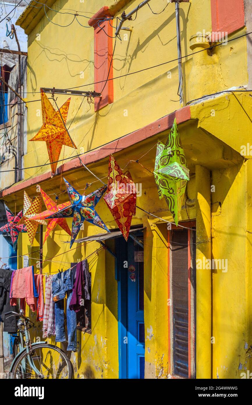 Colorate lanterne a forma di stella appese all'esterno di casa dipinta di giallo con porta blu, Trichy, Tamil Nadu, India Foto Stock