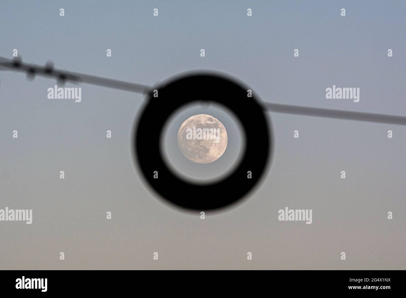 Una luna illuminata è vista sul cielo attraverso una struttura durante la notte di San Giovanni alla spiaggia di Malagueta. Durante la notte del 24 giugno di 2021 l'ultima luna superluna dell'anno corrente conosciuta come 'la luna piena di mirtillo avrà luogo '. Il suo nome deriva dalla raccolta delle fragole e avviene dopo il solstizio estivo. Foto Stock