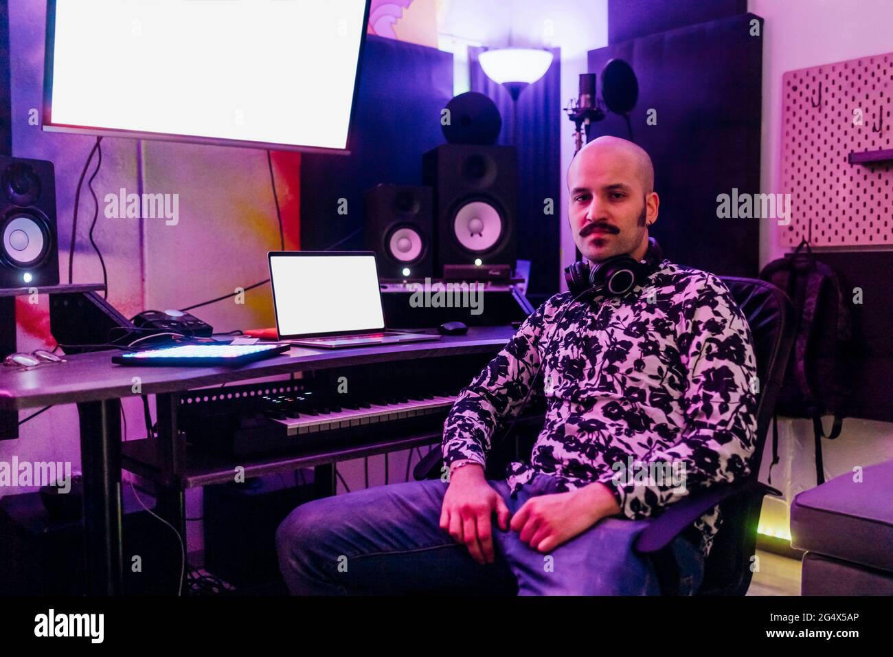 Compositore maschile seduto da apparecchiature audio in studio Foto Stock