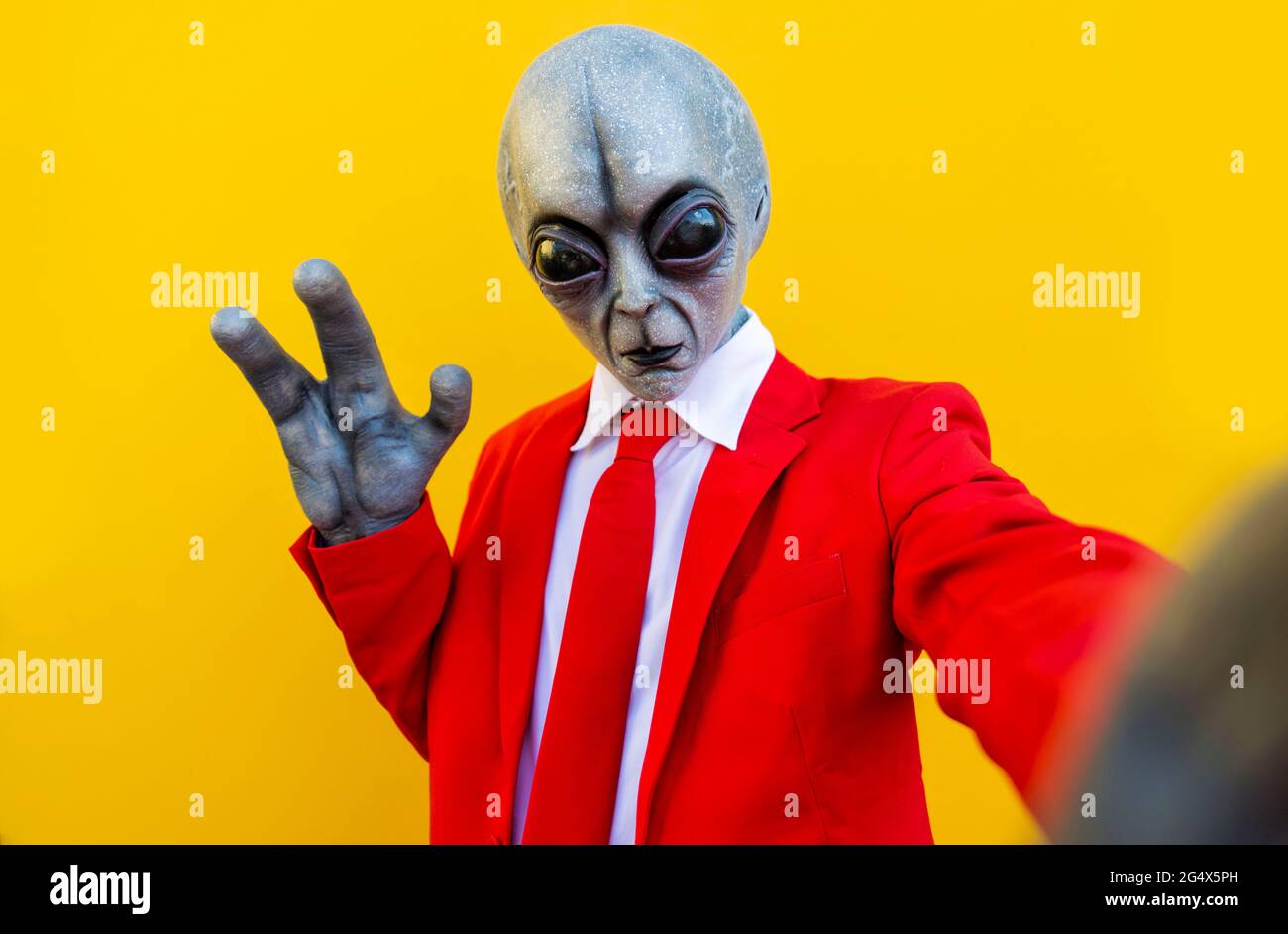 Ritratto di un uomo che indossa un costume alieno e un vestito rosso  brillante che raggiunge la fotocamera Foto stock - Alamy