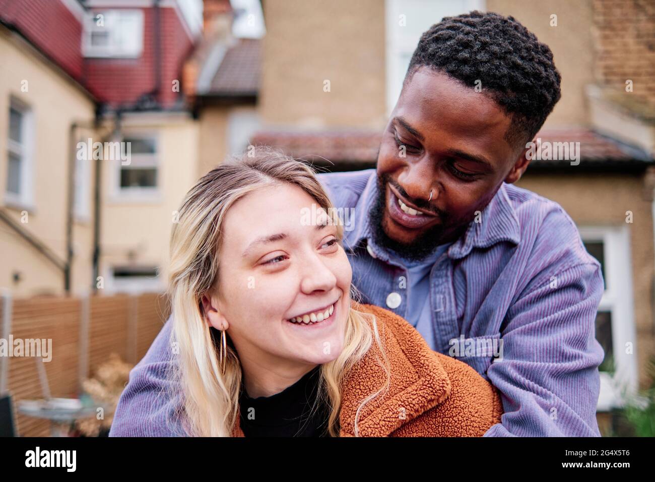 Sorridente ragazzo abbracciando mentre si guarda la ragazza Foto Stock