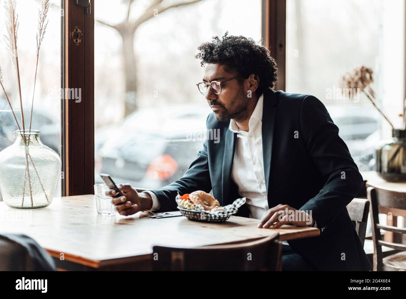 Uomo d'affari che usa lo smartphone mentre pranza al ristorante Foto Stock