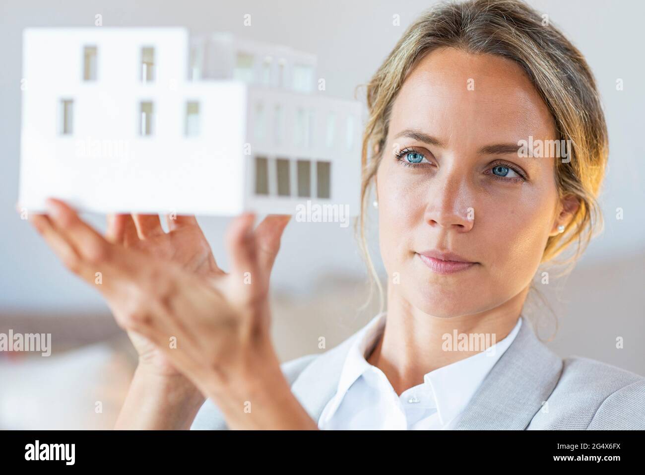 Donna d'affari con gli occhi blu che controlla il modello architettonico in ufficio Foto Stock