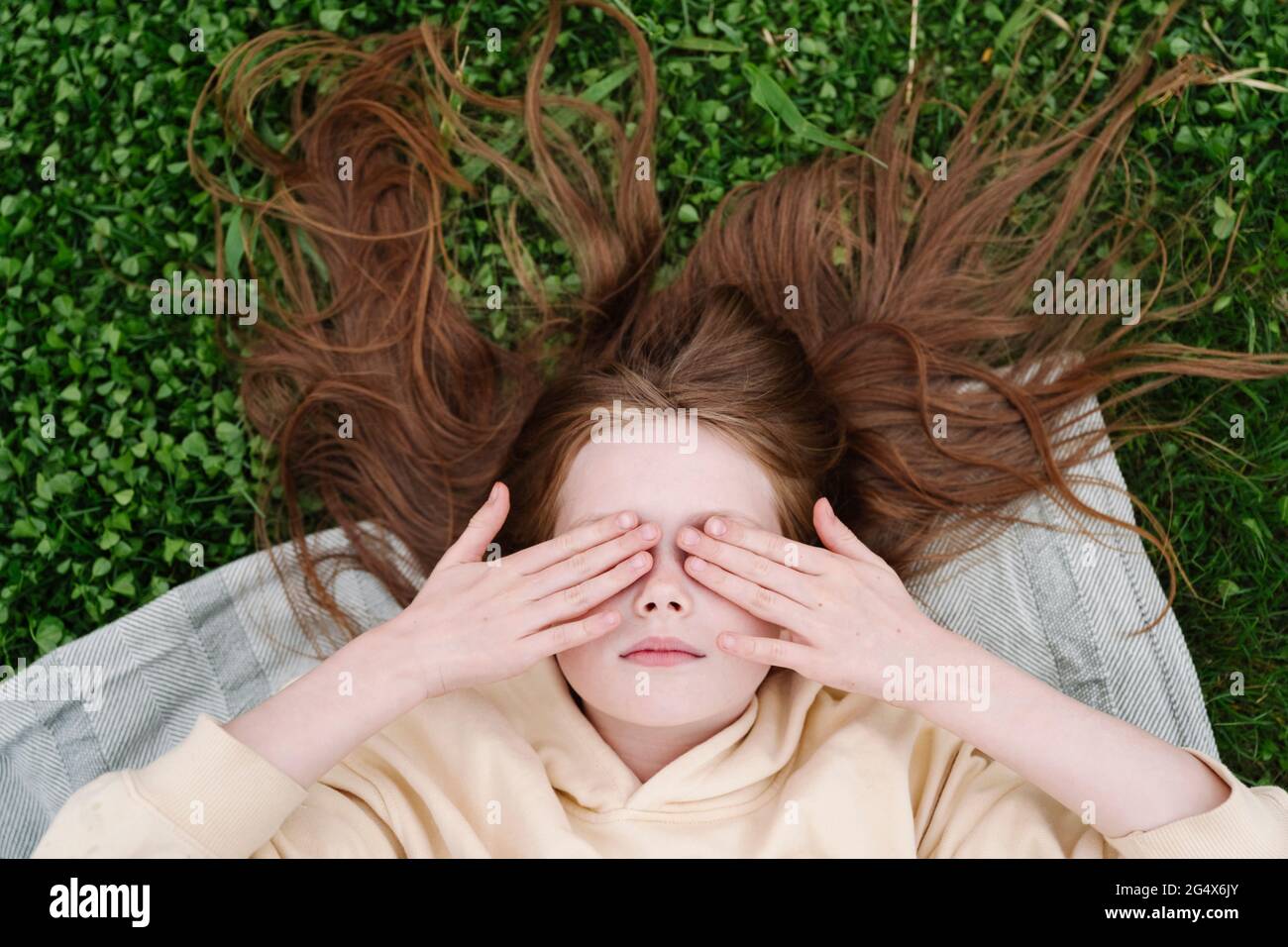 Ragazza con gli occhi coperti mentendo al parco pubblico Foto Stock