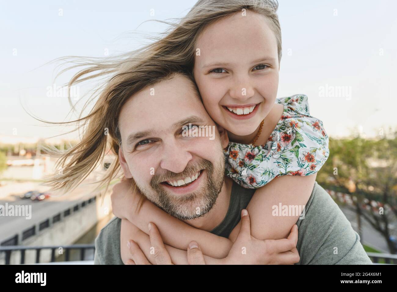 Felice figlia abbracciando padre che porta il suo piggyback Foto Stock