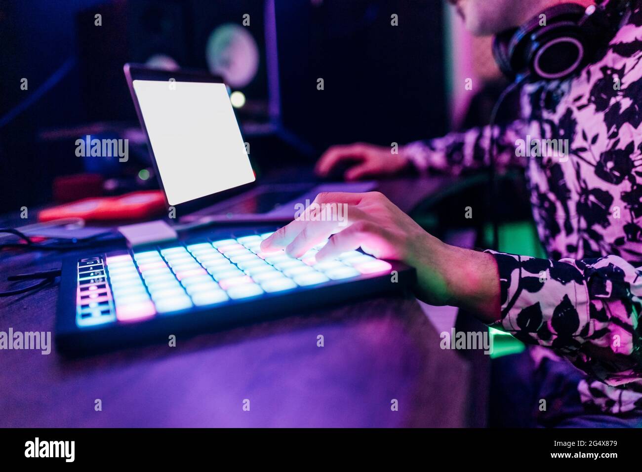 Compositore maschile che compone musica mentre si usa un computer portatile e un tablet digitale in studio Foto Stock