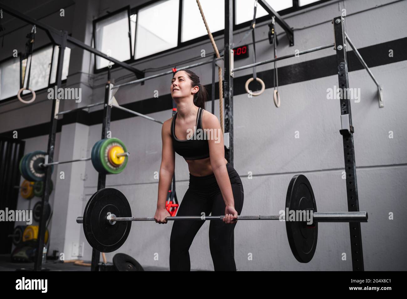 Donna attiva che solleva il peso in palestra Foto Stock