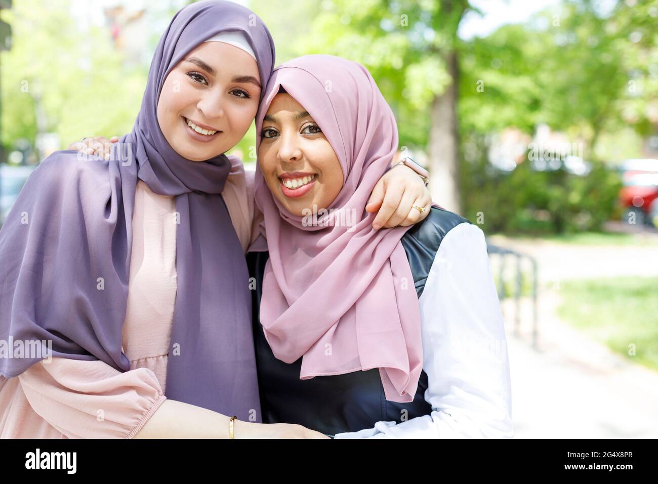 Sorridendo belle donne con le mani sulle spalle in piedi nel parco Foto Stock