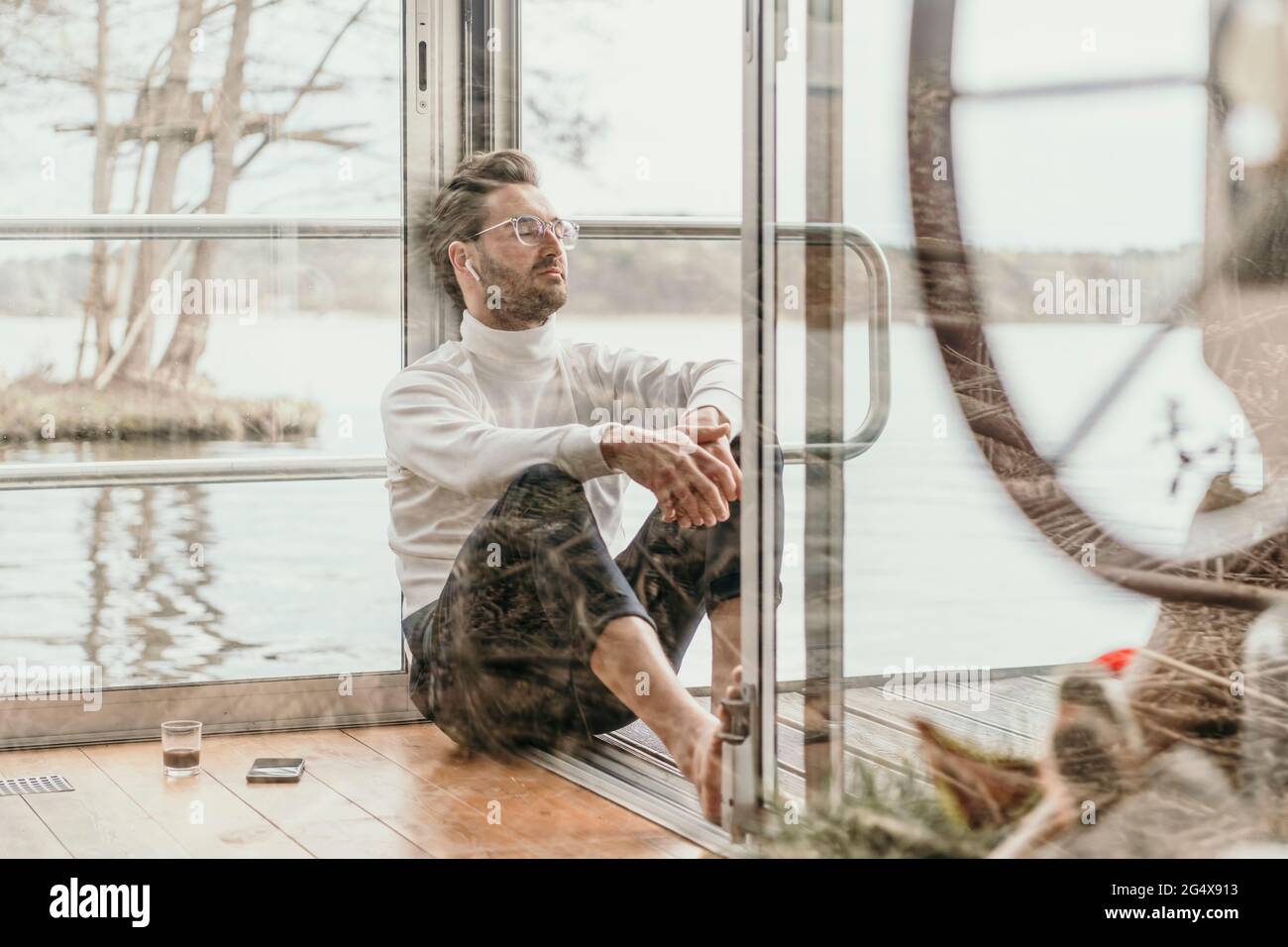 L'uomo rilassato ascoltando musica mentre si siede in casa Foto Stock