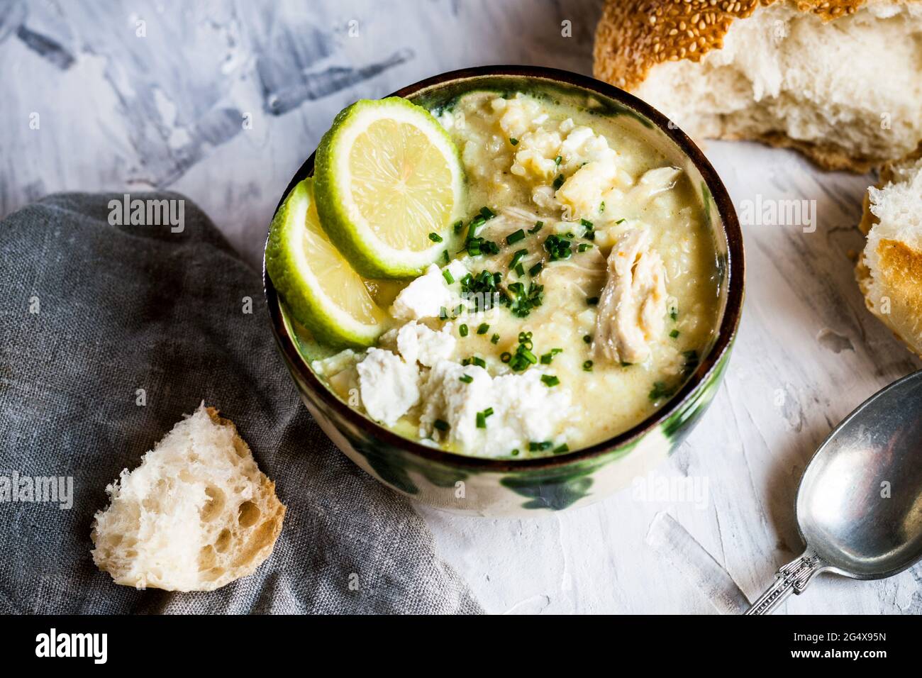 Ciotola di zuppa GreekÂ avgolemonoÂ con riso, fette di limone e pane Foto Stock