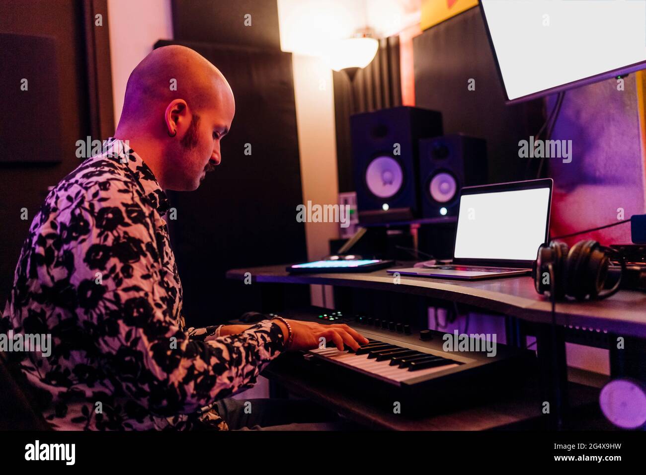 Uomo che suona piano mentre compone musica in studio Foto Stock