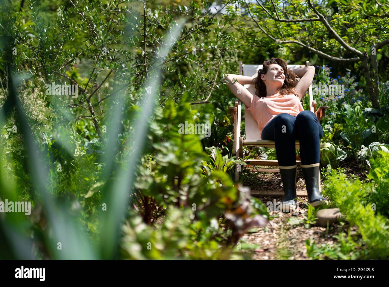 Giovane donna che si rilassa sulla sedia in giardino durante la giornata di sole Foto Stock