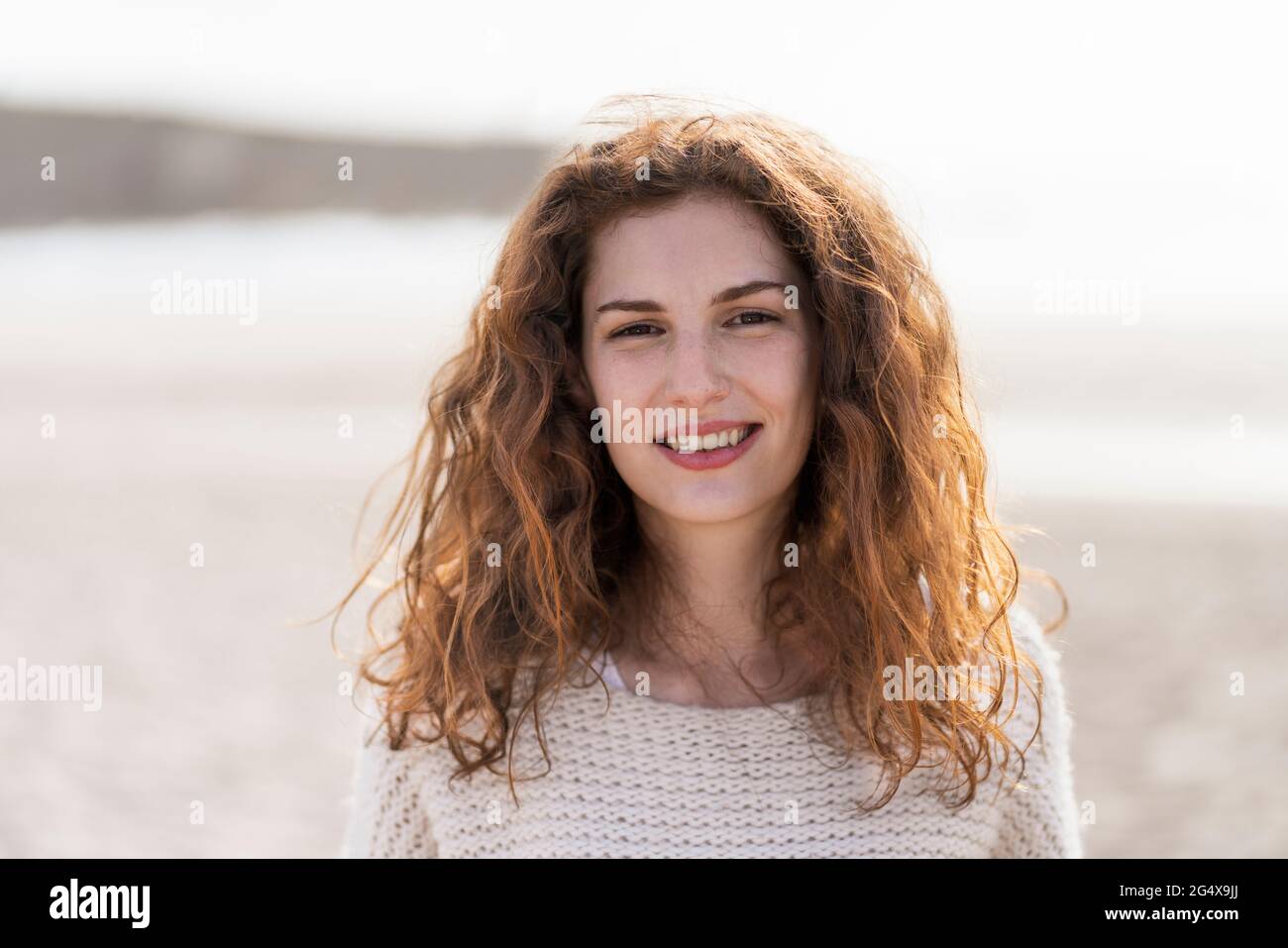 Bella donna rossa sorridente in spiaggia Foto Stock