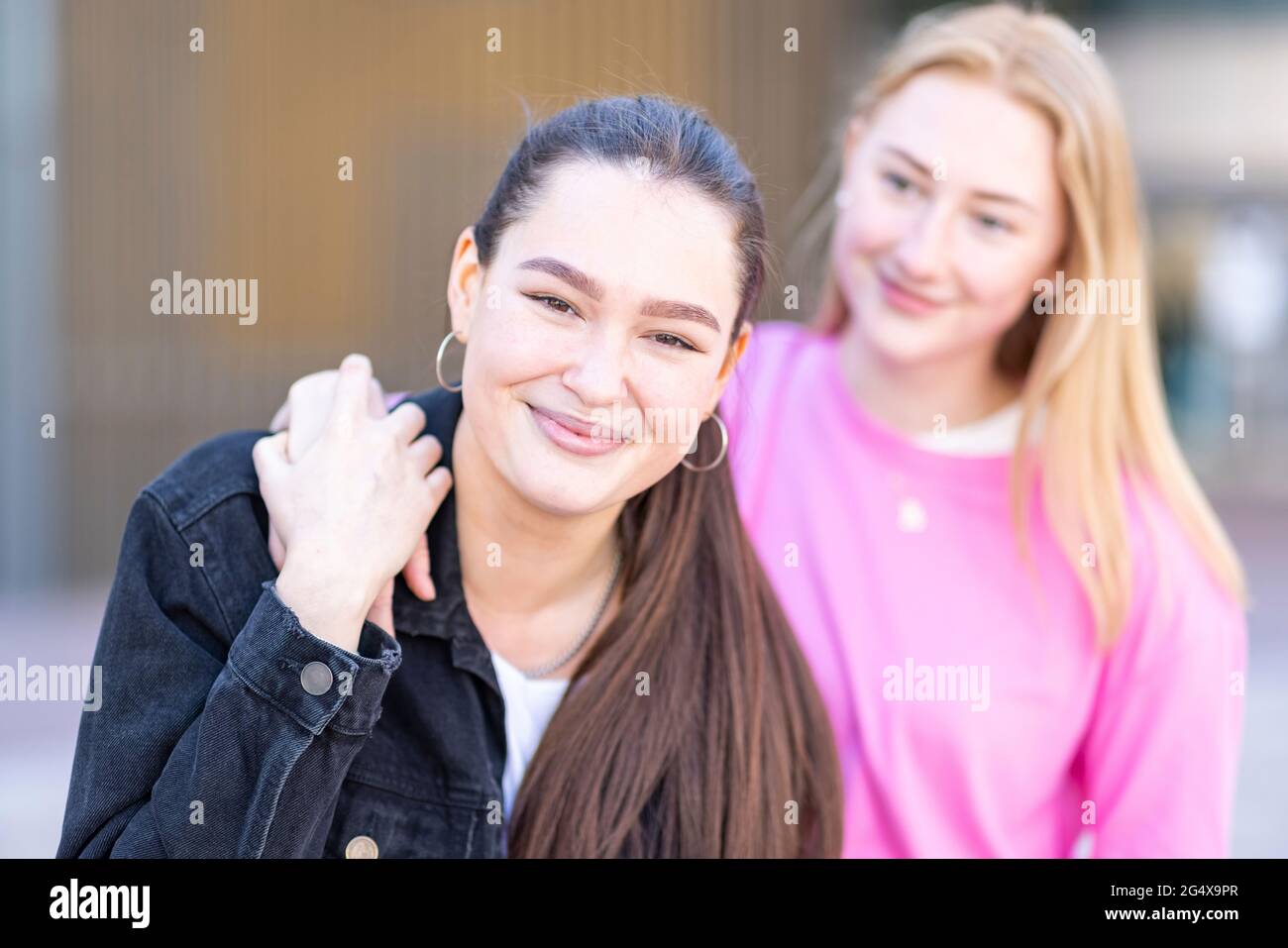 Sorridente bella donna con la mano sulla spalla di femmina amico in città Foto Stock