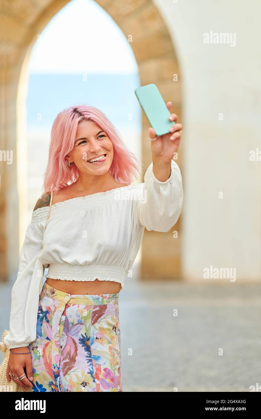 Giovane donna che si stacca dalla lingua mentre prende selfie attraverso il telefono cellulare Foto Stock