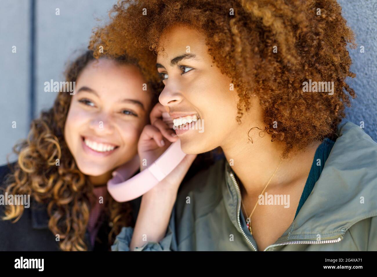 Amici di sesso femminile che condividono le cuffie mentre ascoltano la musica Foto Stock