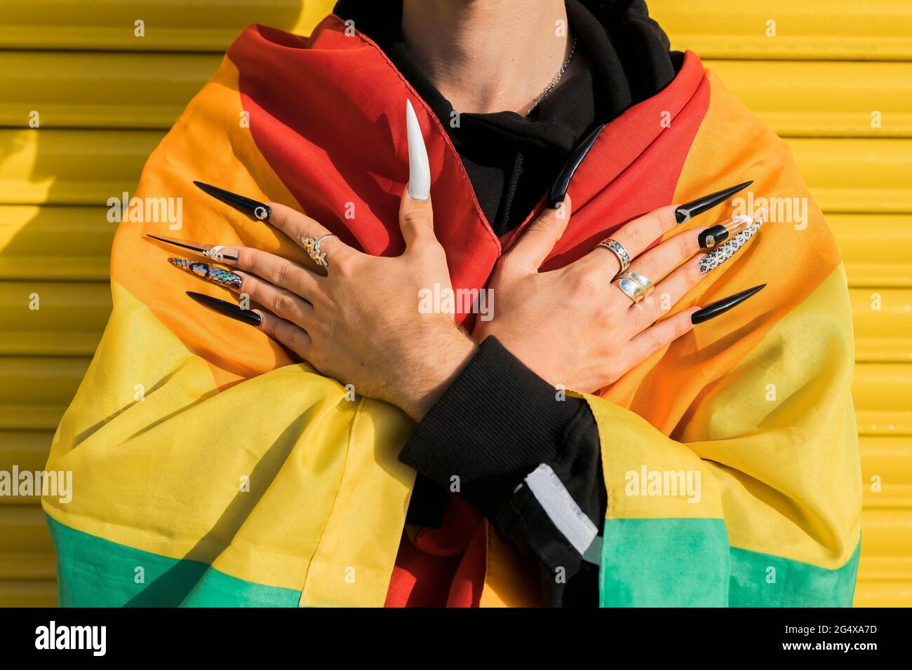 Uomo gay avvolto in bandiera arcobaleno Foto Stock