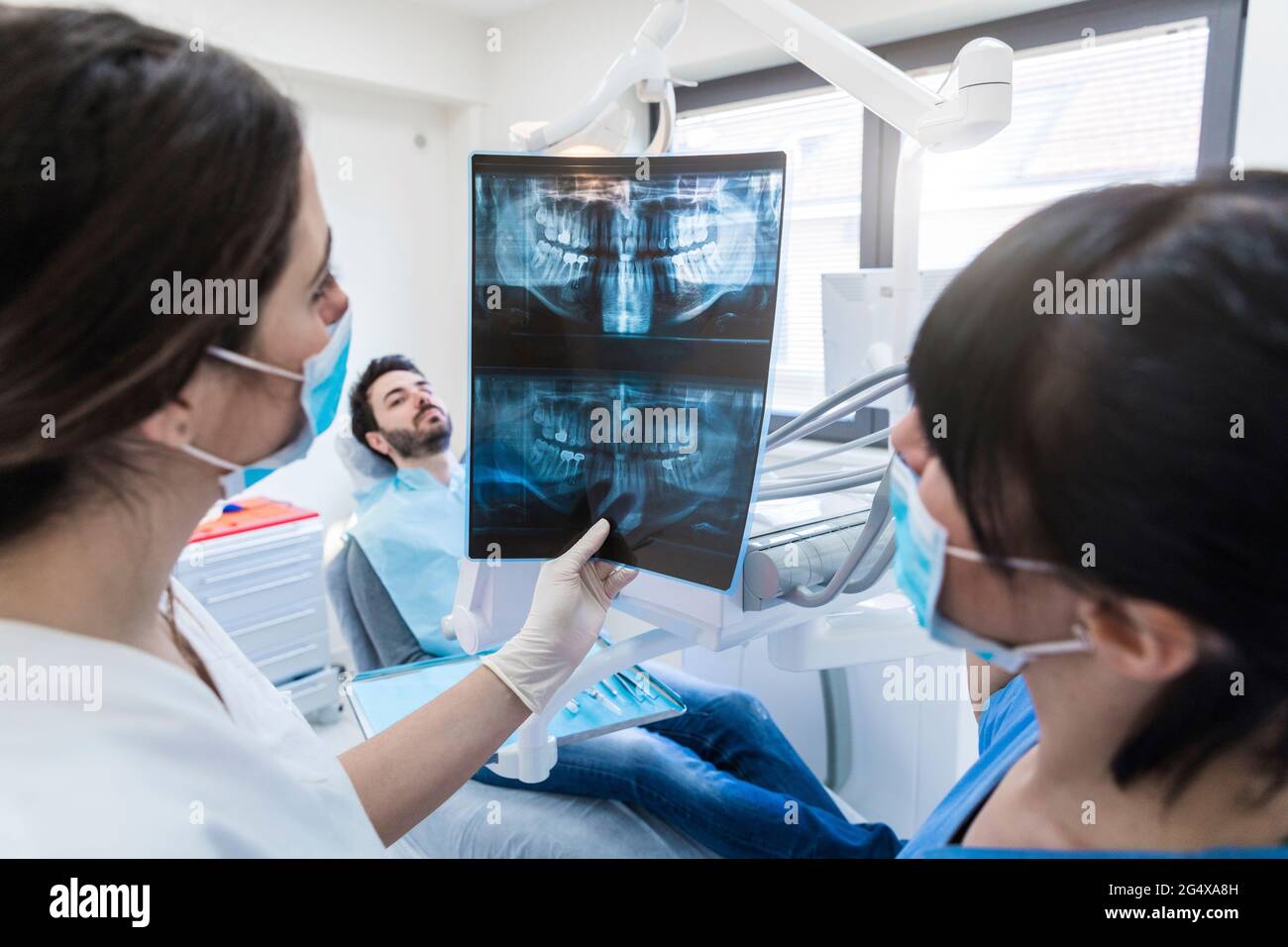 Dentista femminile che mostra raggi X ad assistente in clinica Foto Stock