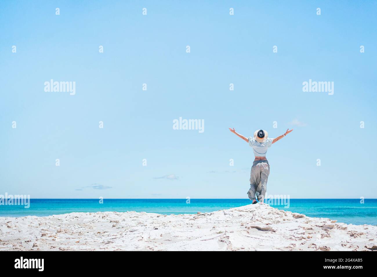 Donna in piedi con le braccia distese sull'isola di Formentera durante le vacanze estive Foto Stock