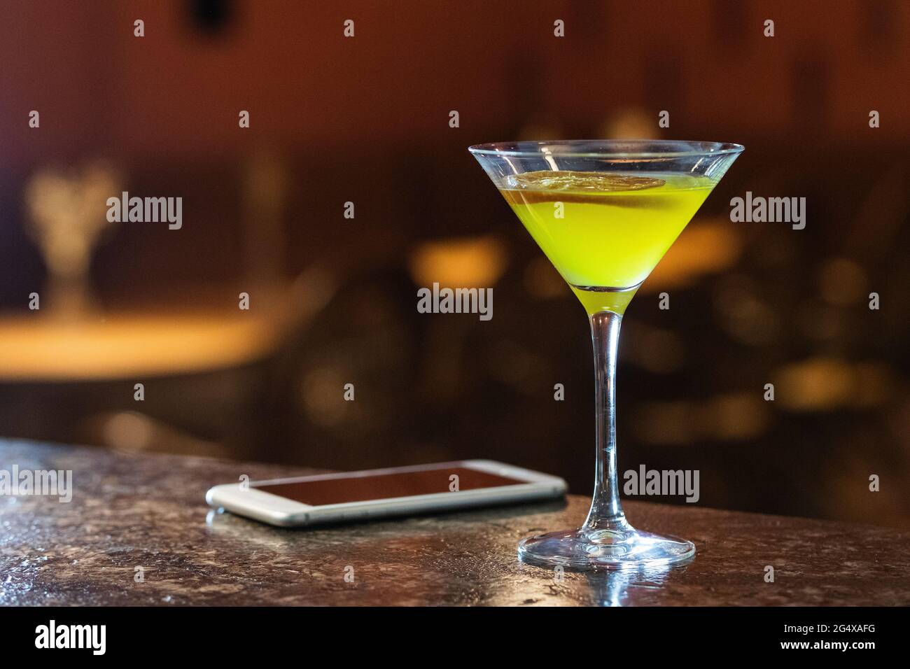 Bere in bicchiere martini dal telefono cellulare sul tavolo Foto Stock
