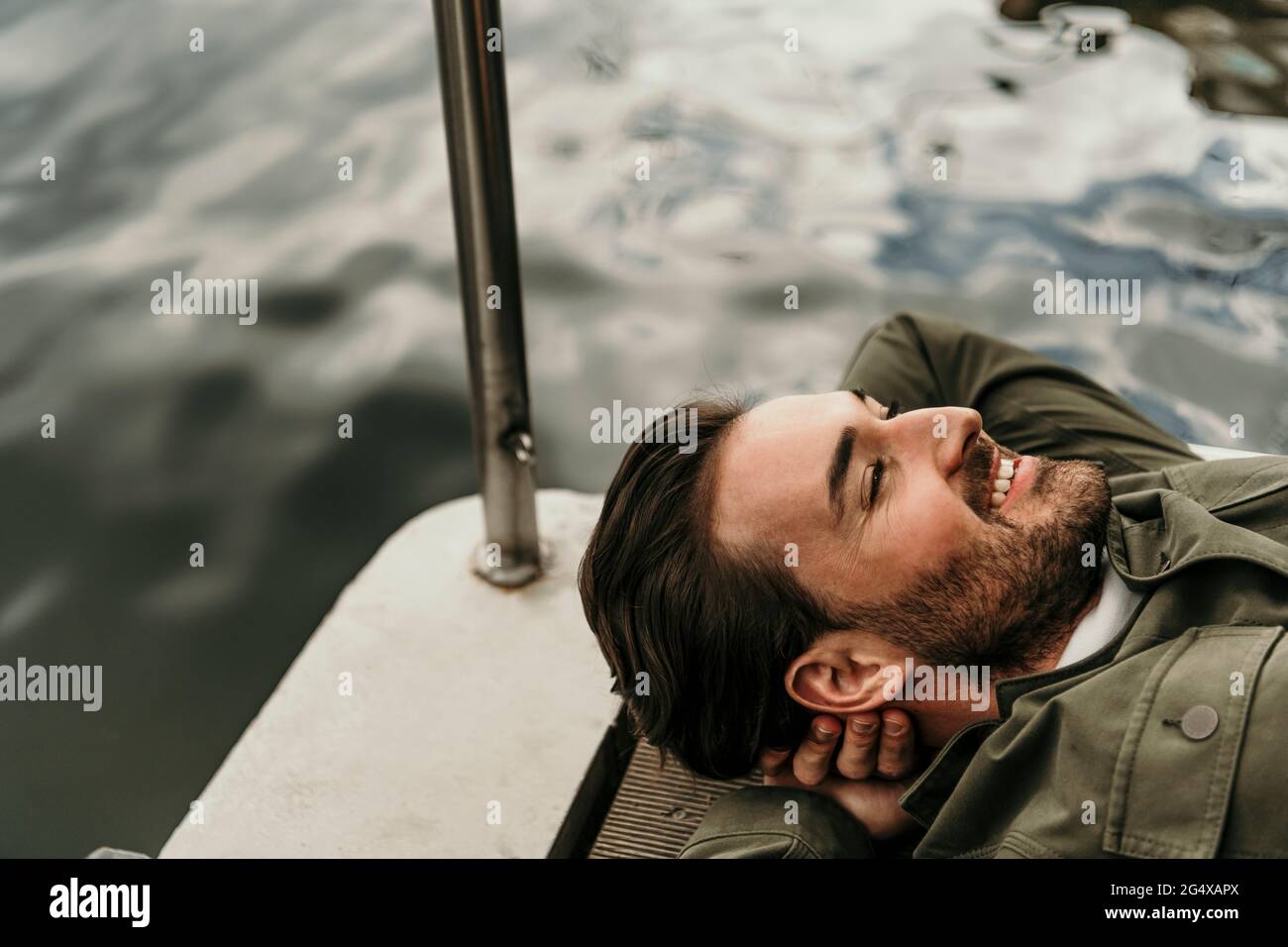 Uomo sorridente che riposa sulla casa galleggiante Foto Stock