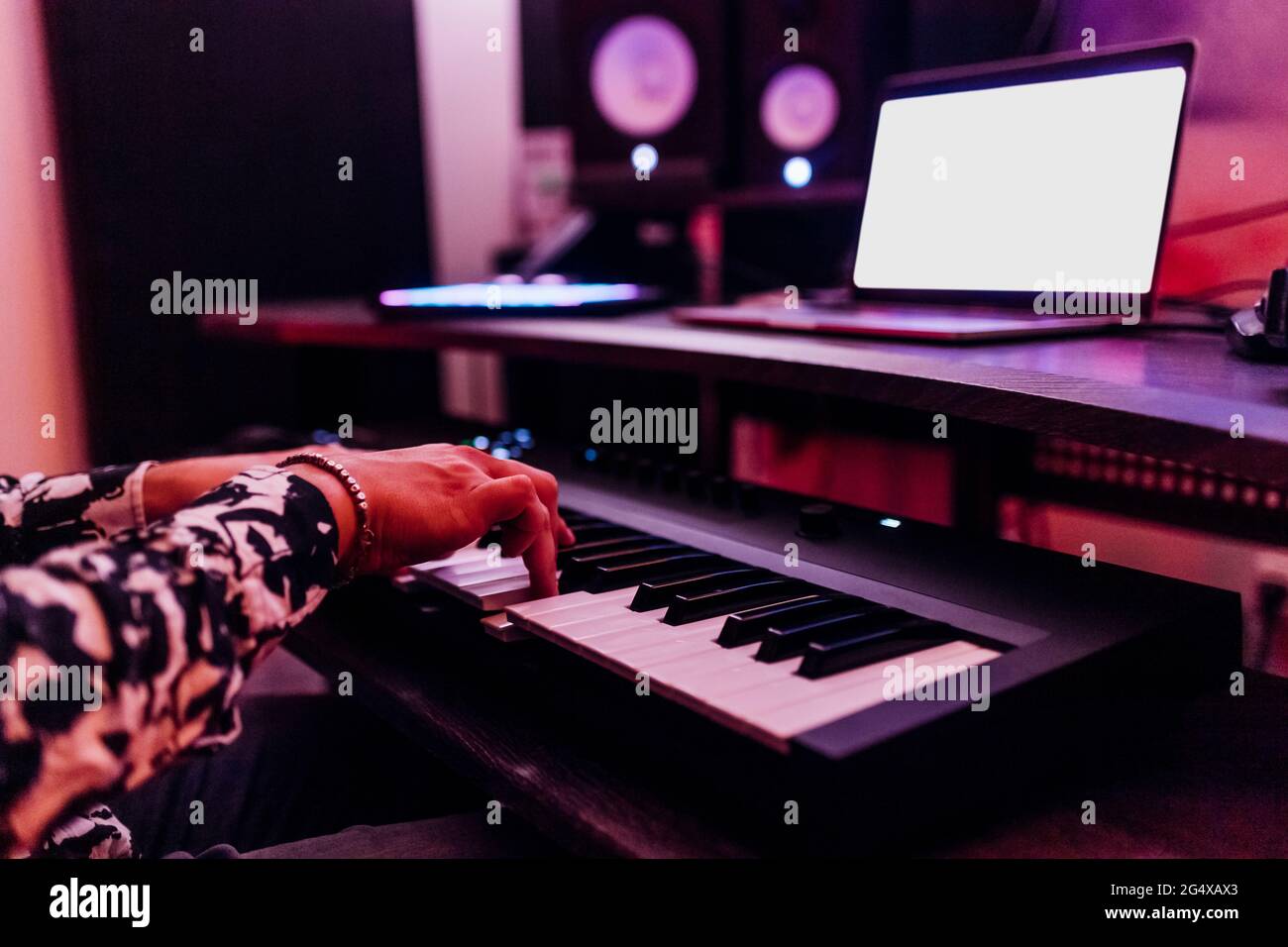 Giovane compositore maschile che suona piano davanti al computer portatile in studio Foto Stock