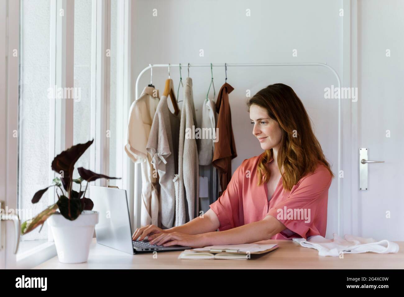 Donna stilista di moda che usa un computer portatile mentre lavora a casa Foto Stock