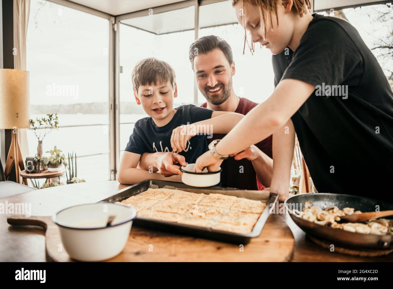 Sorridente padre con figli che preparano il cibo in cucina a houseboat Foto Stock