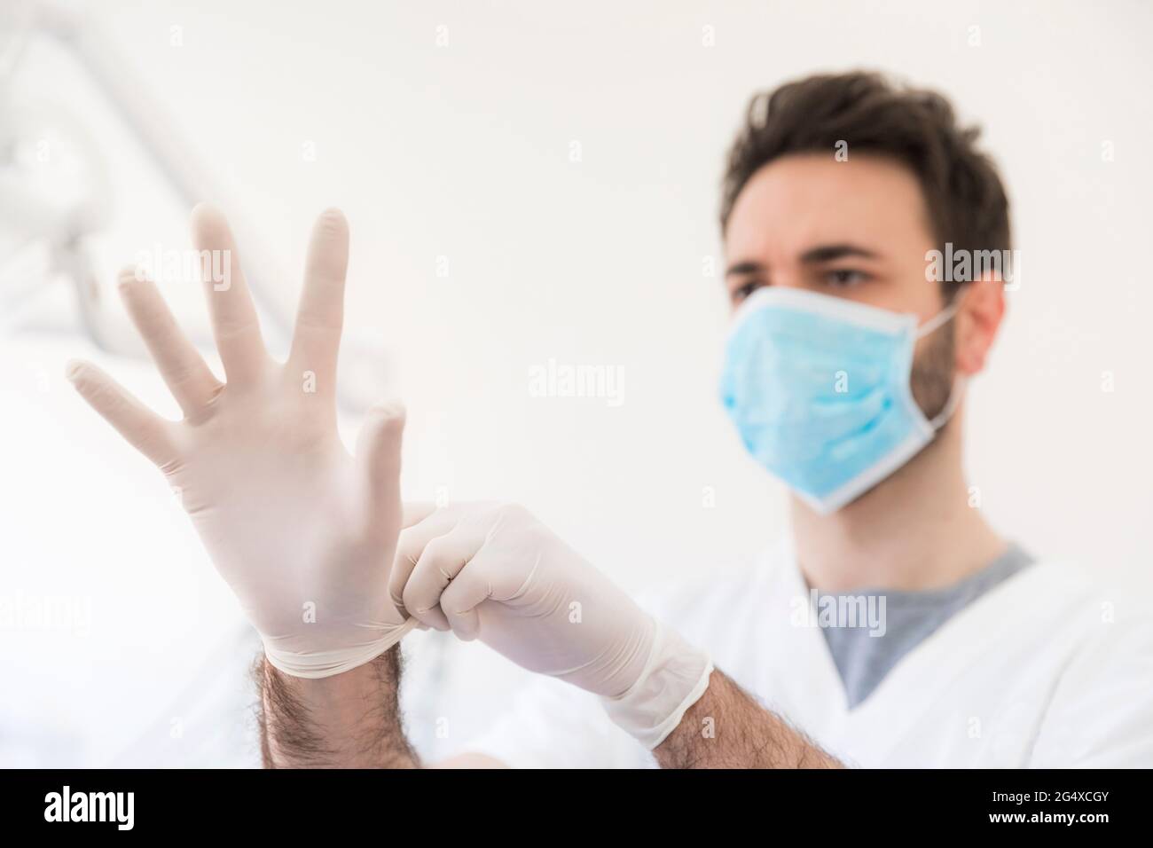 Dentista maschile indossando guanti protettivi presso la clinica medica Foto Stock