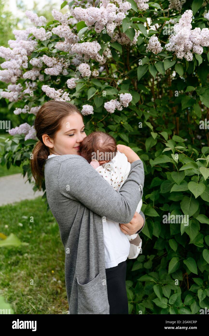 Ragazza abbracciando sorella mentre si sta in piedi da piante fiorite Foto Stock
