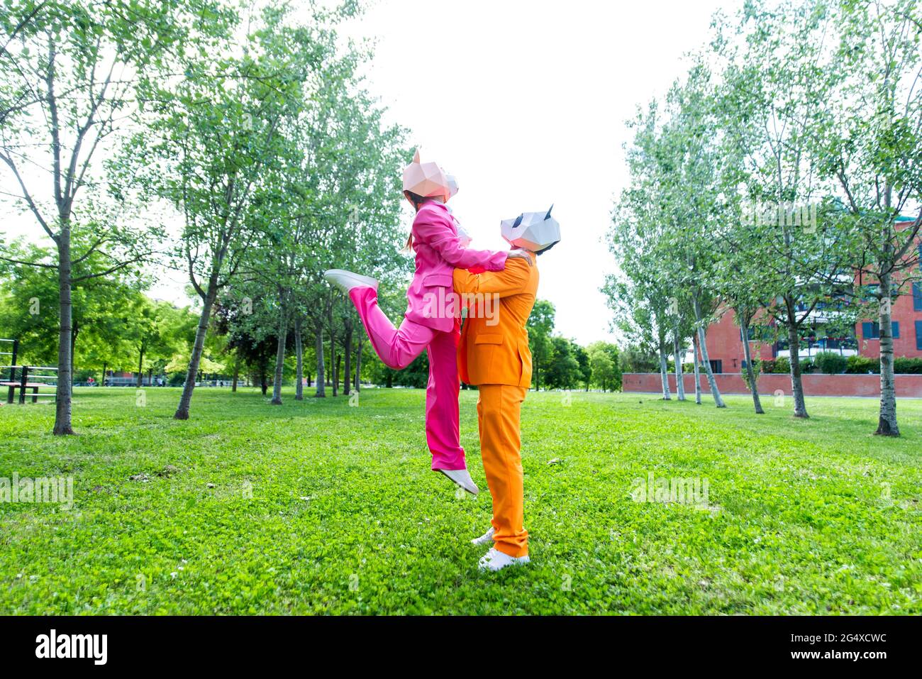 coupleÂ adulto indossa abiti vivaci e maschere animali che giocano nel parco pubblico Foto Stock