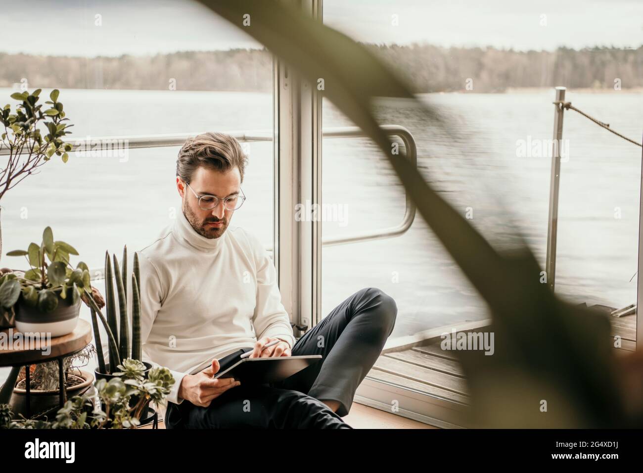 Uomo d'affari che utilizza un tablet digitale mentre lavora in casa Foto Stock