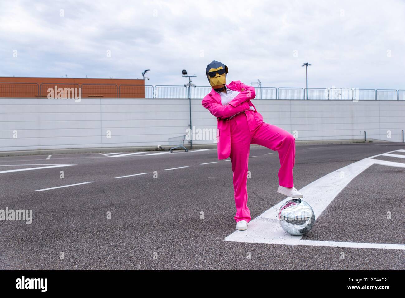 Personaggio divertente che indossa maschera animale e vestito da lavoro rosa divertirsi nel parcheggio vuoto Foto Stock
