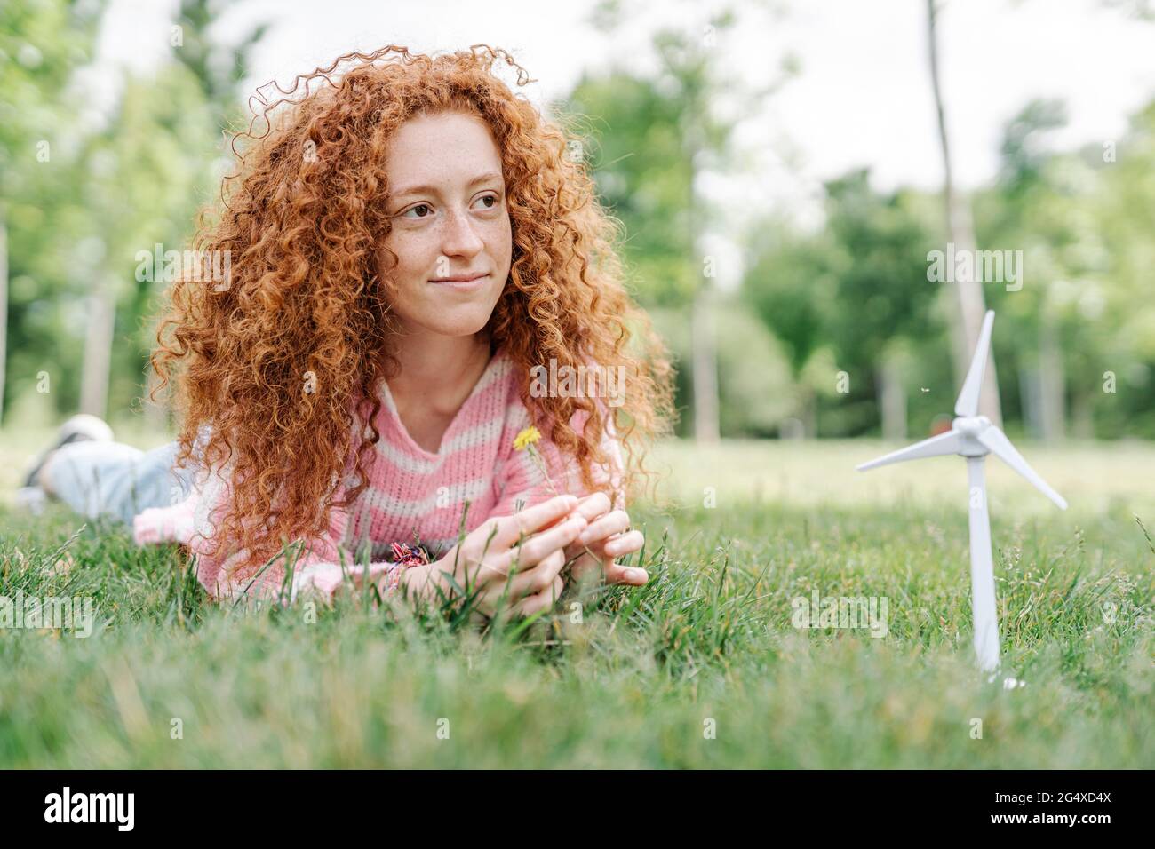 Giovane donna rossa sdraiata nel parco mentre si guarda via Foto Stock