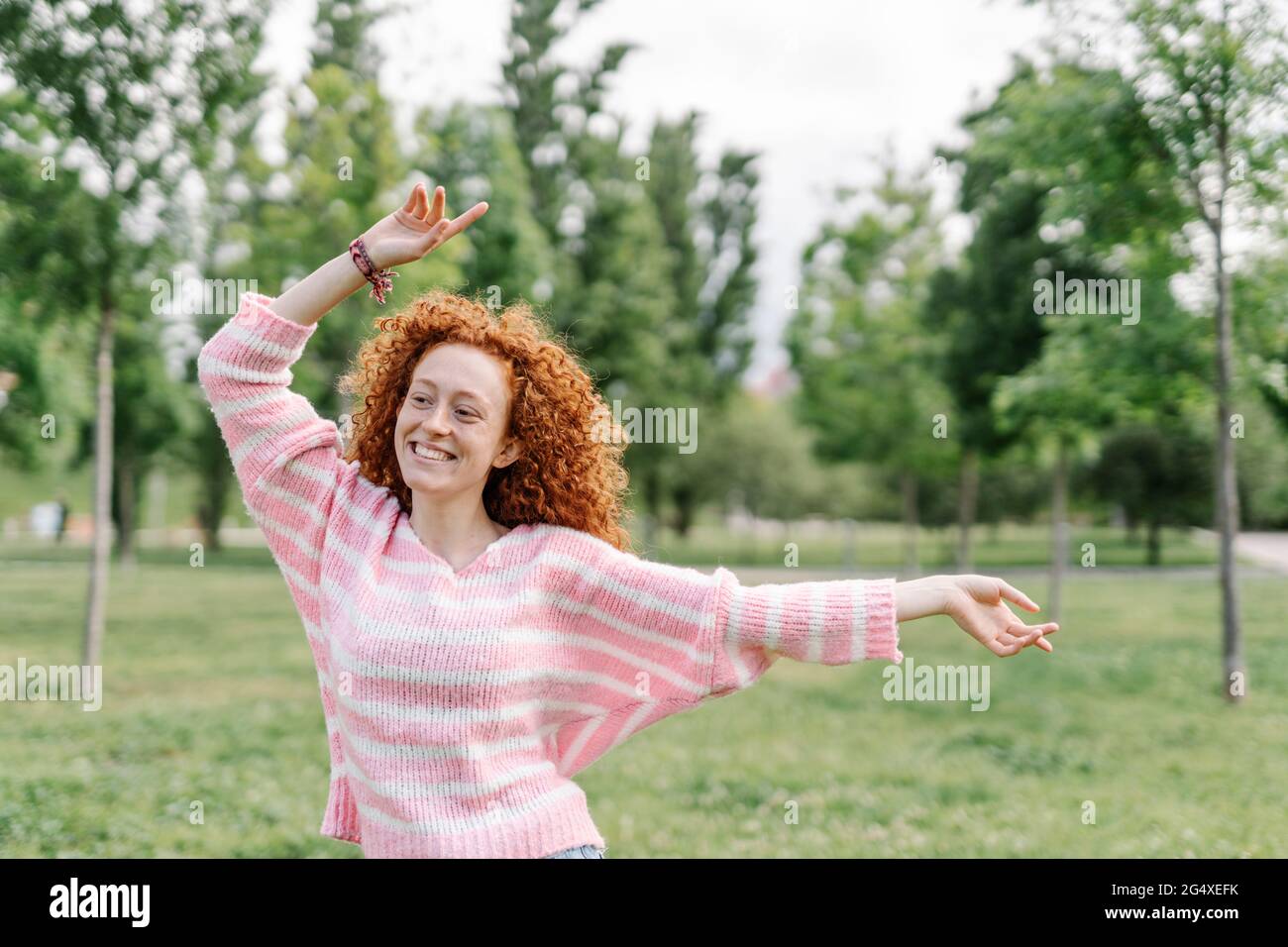 Allegra donna rossa che balla al parco Foto Stock